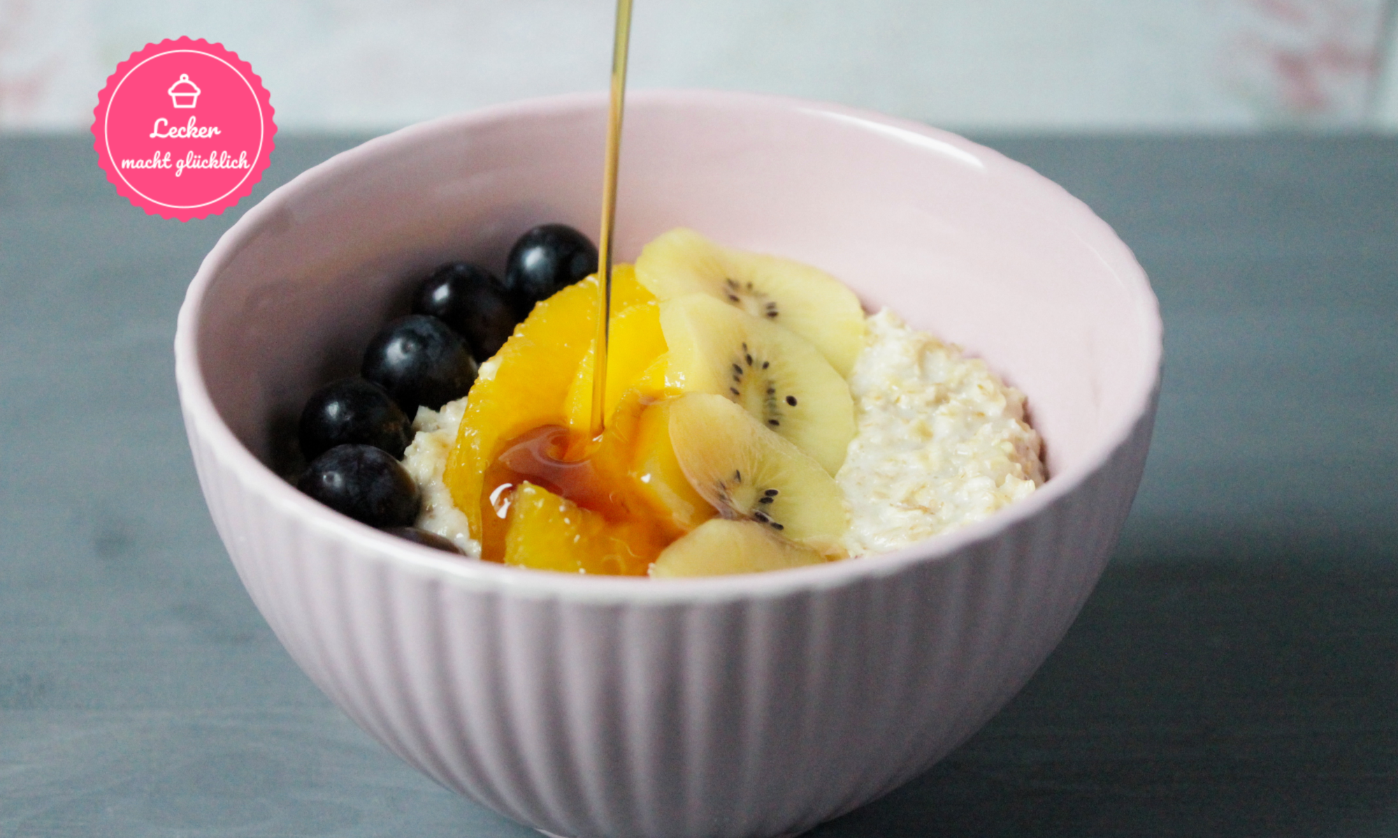 Schüssel mit Porridge und Obst, von oben wird Sirup eingeschüttet