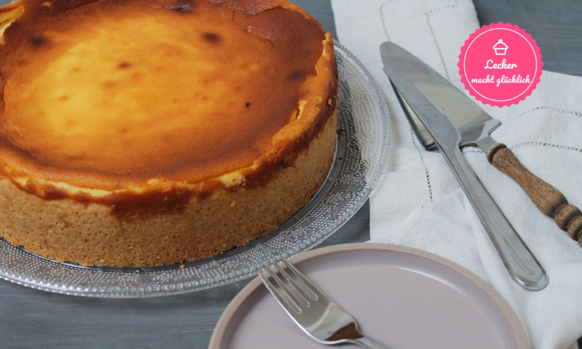 Käsekuchen mit Tortenheber, Messer und Teller mit Gabel